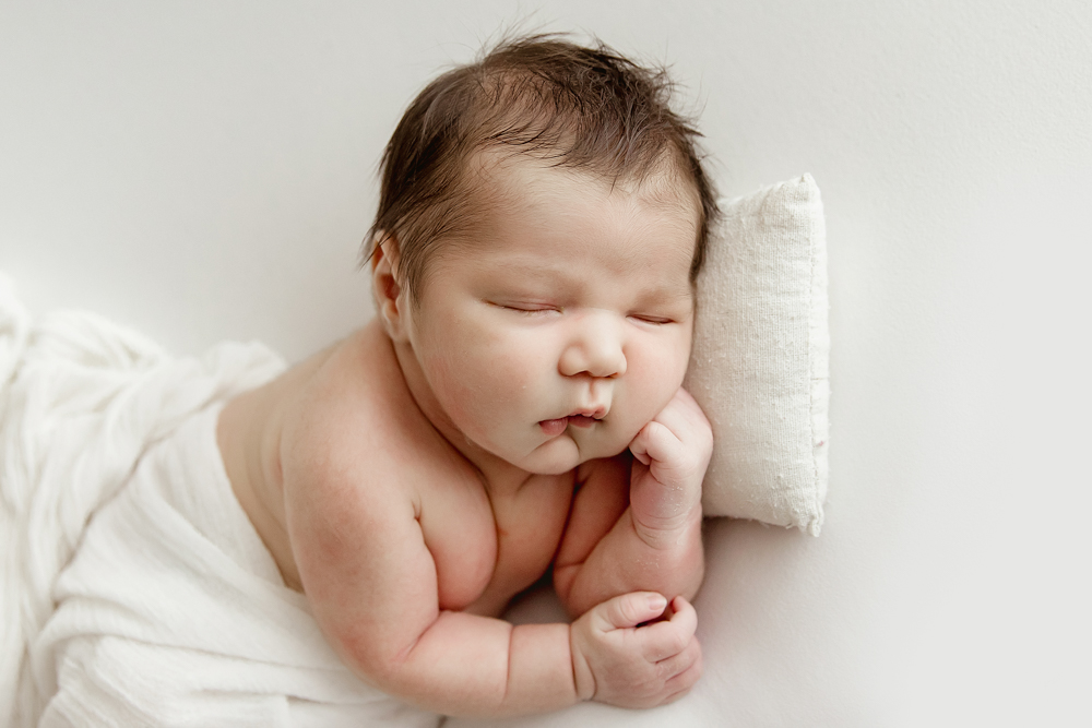 Finn in white wrap resting on tummy, head on tiny pillow, peaceful expression at Reflection Images by Tracy Rowell in Florence SC