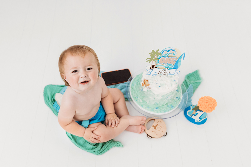Overhead view of Levi smiling up beside his birthday cake, surrounded by green blankets and decorations at Reflection Images by Tracy Rowell in Florence SC