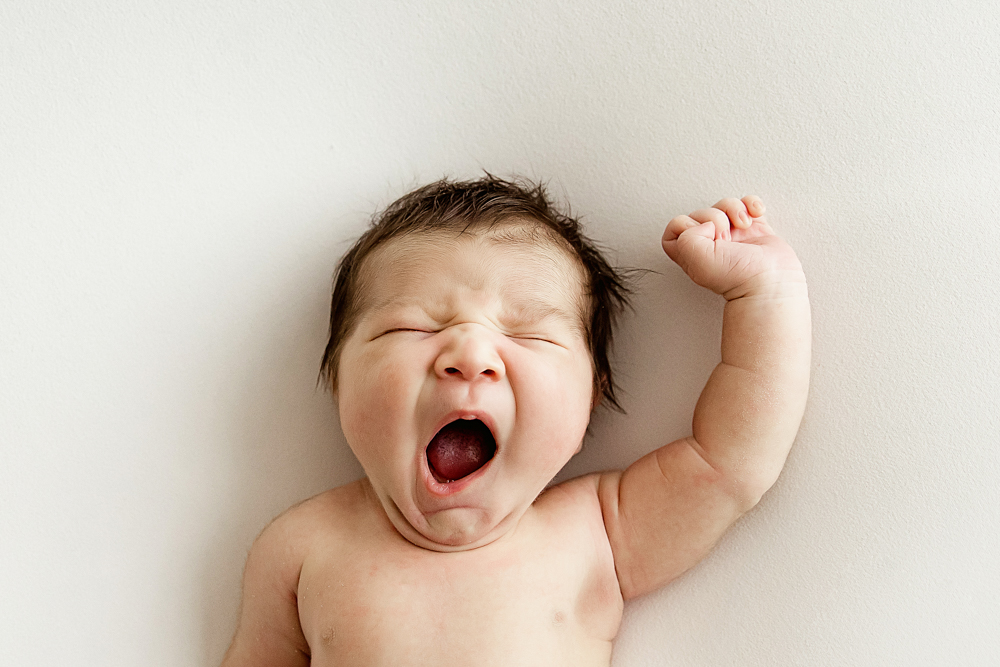 Newborn Finn captured mid-yawn, arm stretched in natural newborn pose at Reflection Images by Tracy Rowell in Florence SC