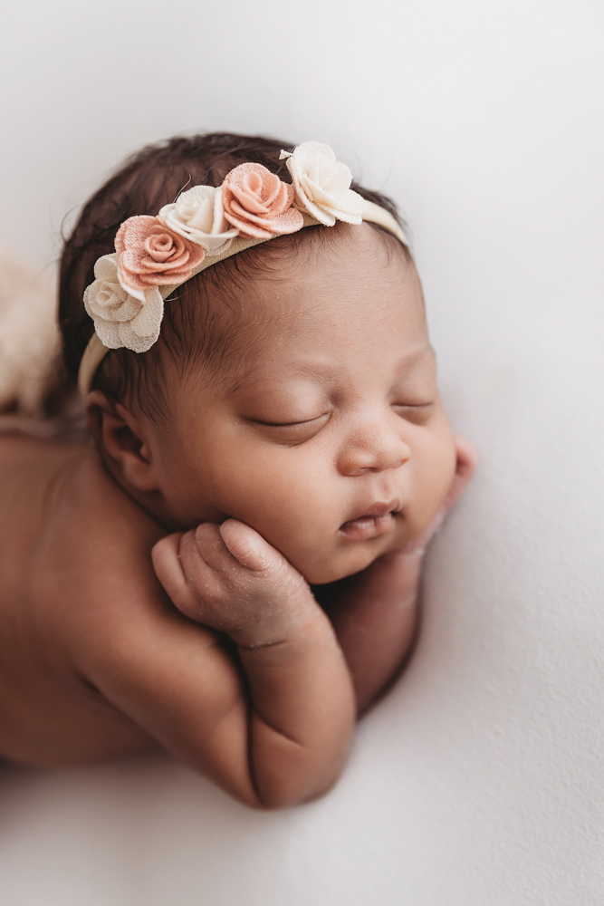 Close-up of Harlem resting on her arms during tummy pose, peach and cream floral crown on her head at Reflection Images by Tracy Rowell in Florence SC
