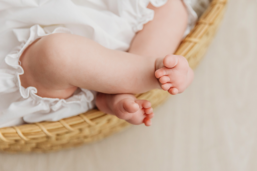 Close-up detail of Mary Katherines tiny baby toes curled inside a wicker basket at Reflection Images by Tracy Rowell in Florence SC