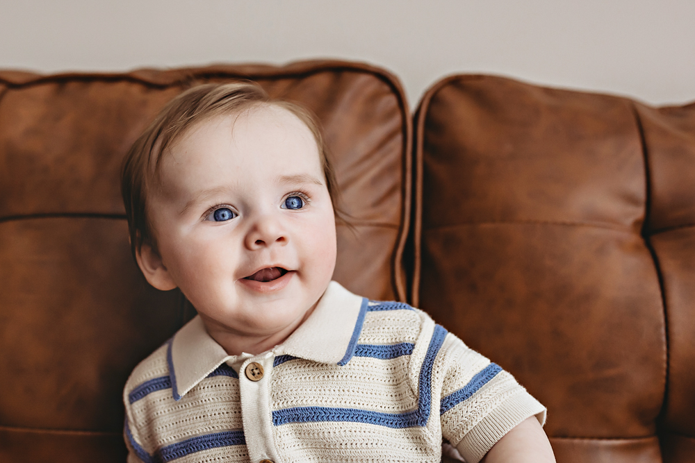 Baby boy looking up and smiling on couch, professional photography studio near Florence SC