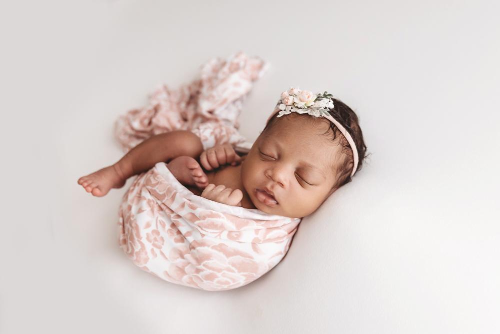 Harlem swaddled in a pink floral wrap with matching headband, side-lying pose on a white blanket at Reflection Images by Tracy Rowell in Florence SC