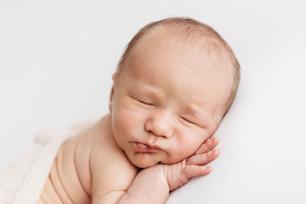 Close-up of baby Harry resting peacefully with hand tucked under cheek at Reflection Images by Tracy Rowell in Florence SC