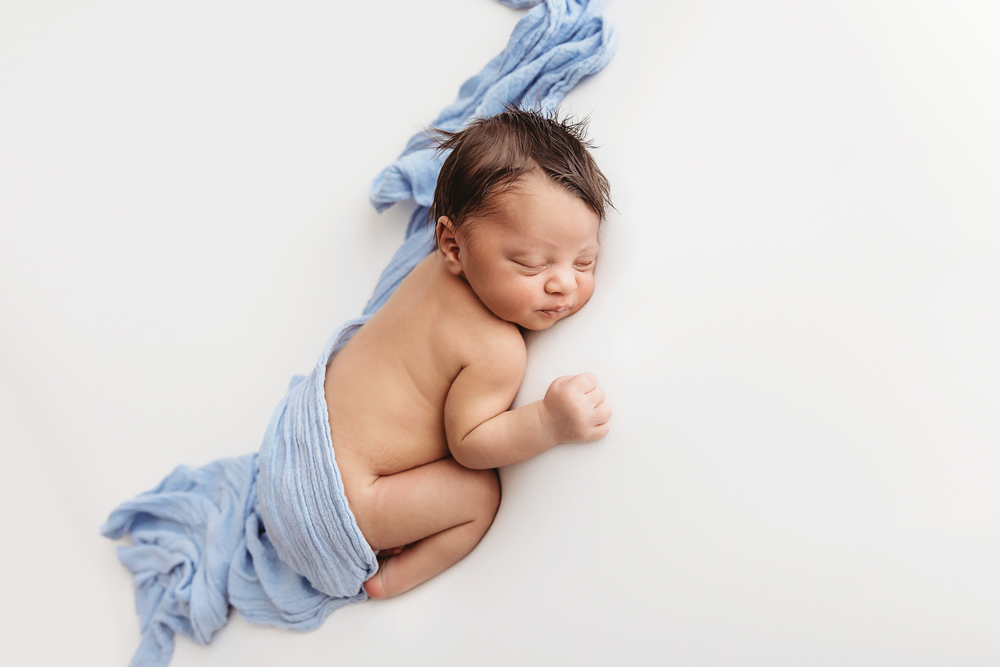 Liston posed in a taco-style position with soft blue wrap and curled body on a white blanket at Reflection Images by Tracy Rowell in Florence SC