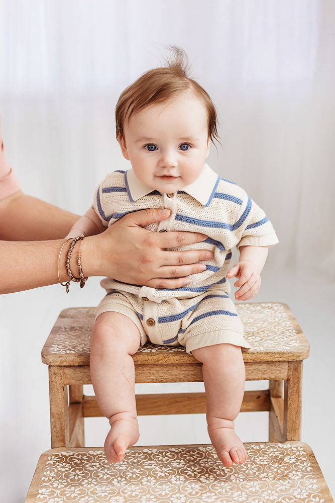 Baby boy being steadied on stool during milestone session, professional newborn photographer Florence SC