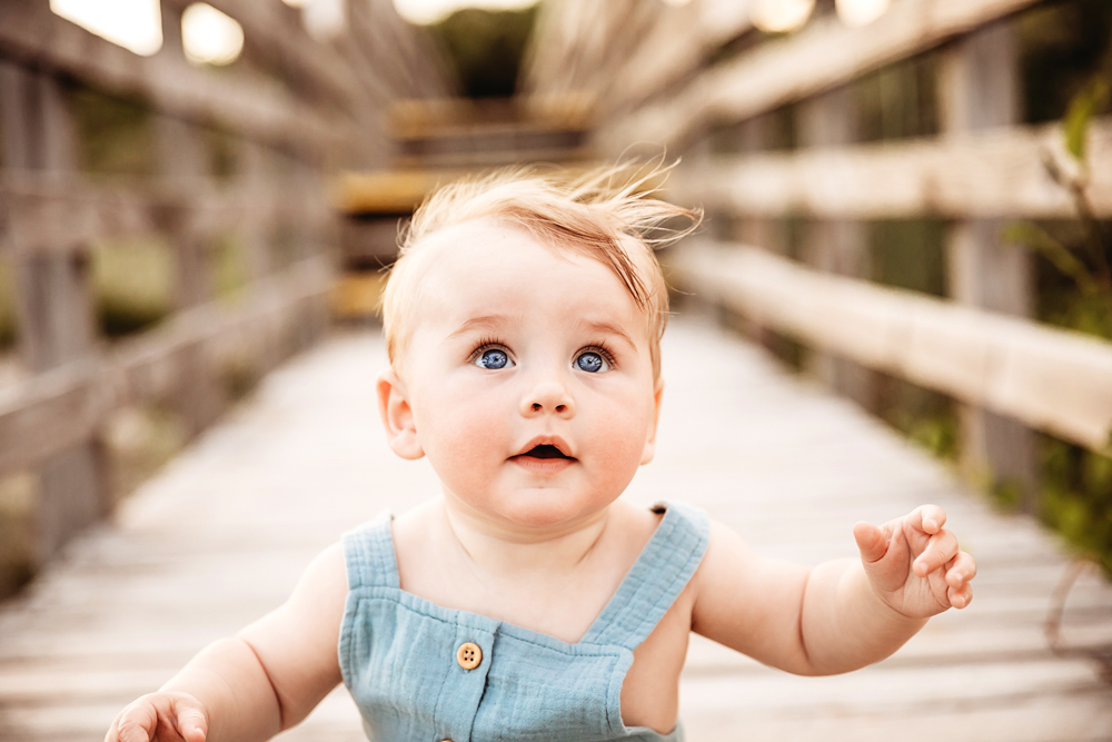 Close-up of Cole's bright blue eyes and windswept hair on a rustic beach boardwalk at Reflection Images by Tracy Rowell in Florence SC