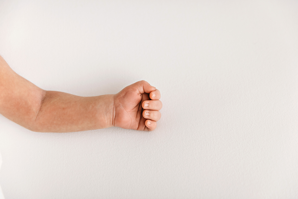 Macro close-up of newborn Listons tiny clenched hand resting on a clean white background at Reflection Images by Tracy Rowell in Florence SC