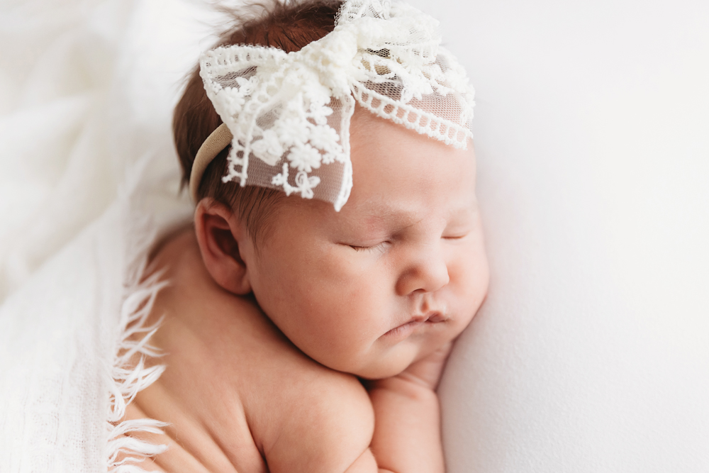 Macro close-up of babys face with lace bow headband at Reflection Images by Tracy Rowell in Florence SC.