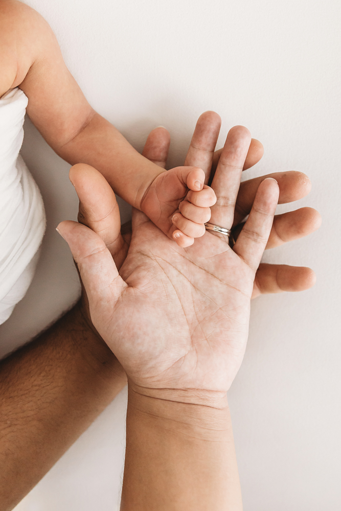 Listons tiny hand wrapped around both parents palms in a heartwarming close-up at Reflection Images by Tracy Rowell in Florence SC