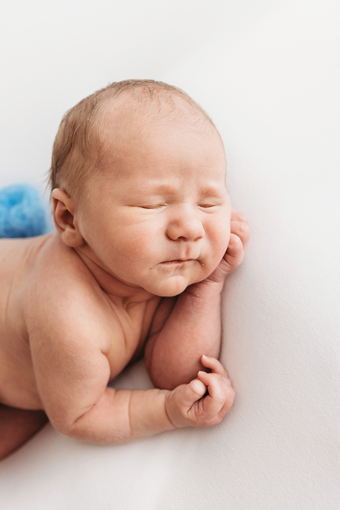 Close-up profile of baby Harry with blue knit diaper cover and hand resting on cheek at Reflection Images by Tracy Rowell in Florence SC