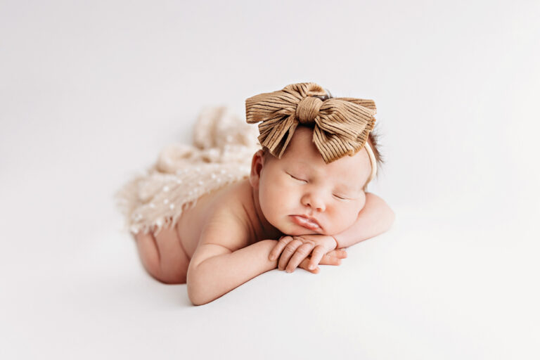 Baby posed tummy time style with large tan bow headband at Reflection Images by Tracy Rowell in Florence SC.