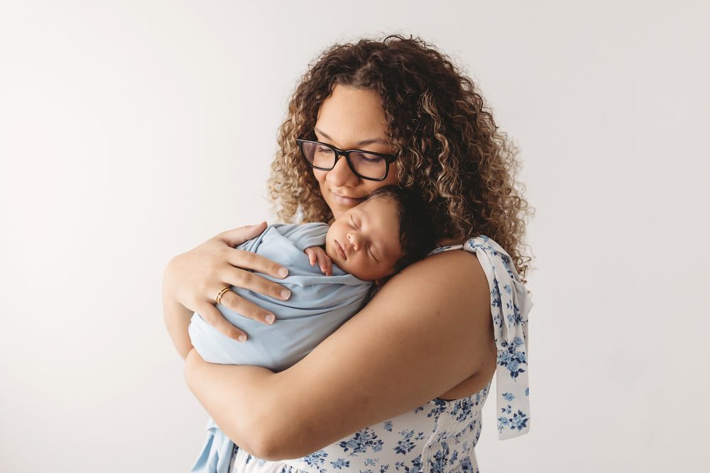 Mom cradling newborn Liston wrapped in blue against her chest, both serene and relaxed at Reflection Images by Tracy Rowell in Florence SC