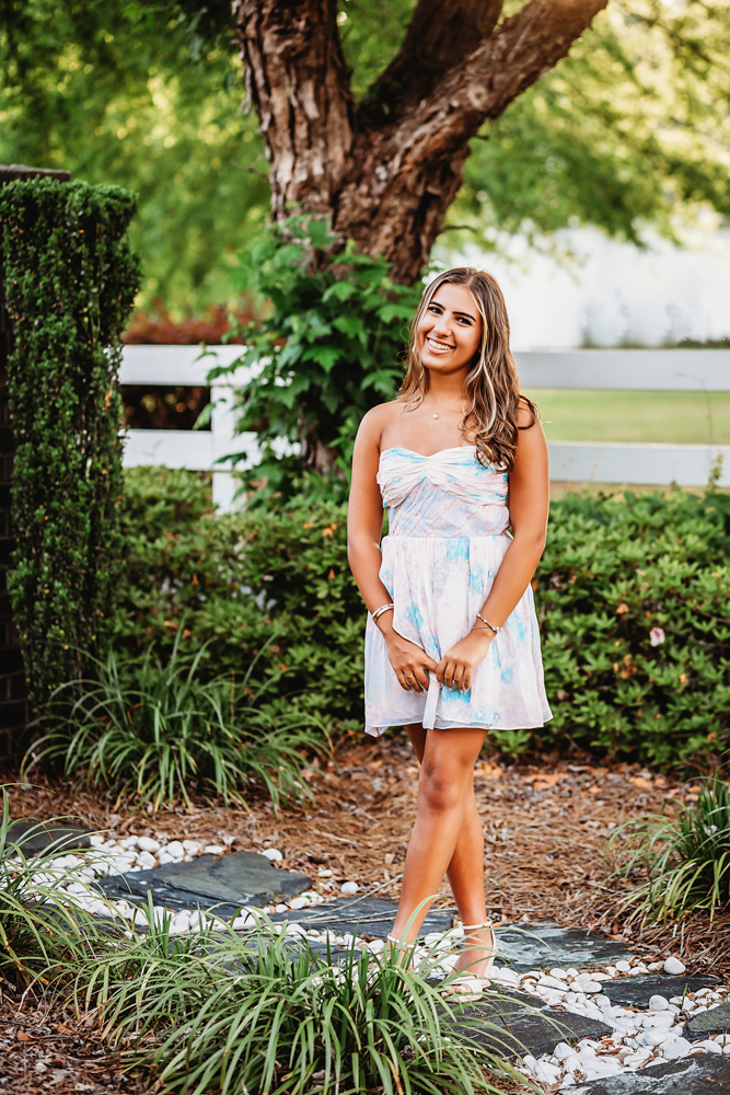 gravel path at golden hour, showing a laughing pose in floral dress from a full-body angle at Reflection Images by Tracy Rowell in Florence SC.