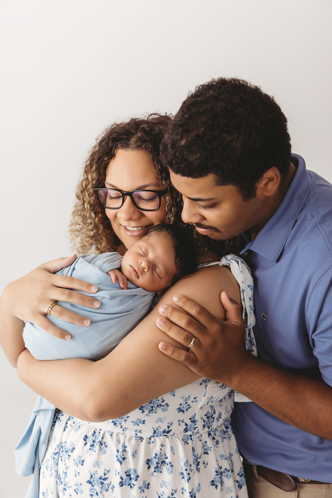 Parents embracing newborn Liston swaddled in soft blue, tender moment captured at Reflection Images by Tracy Rowell in Florence SC