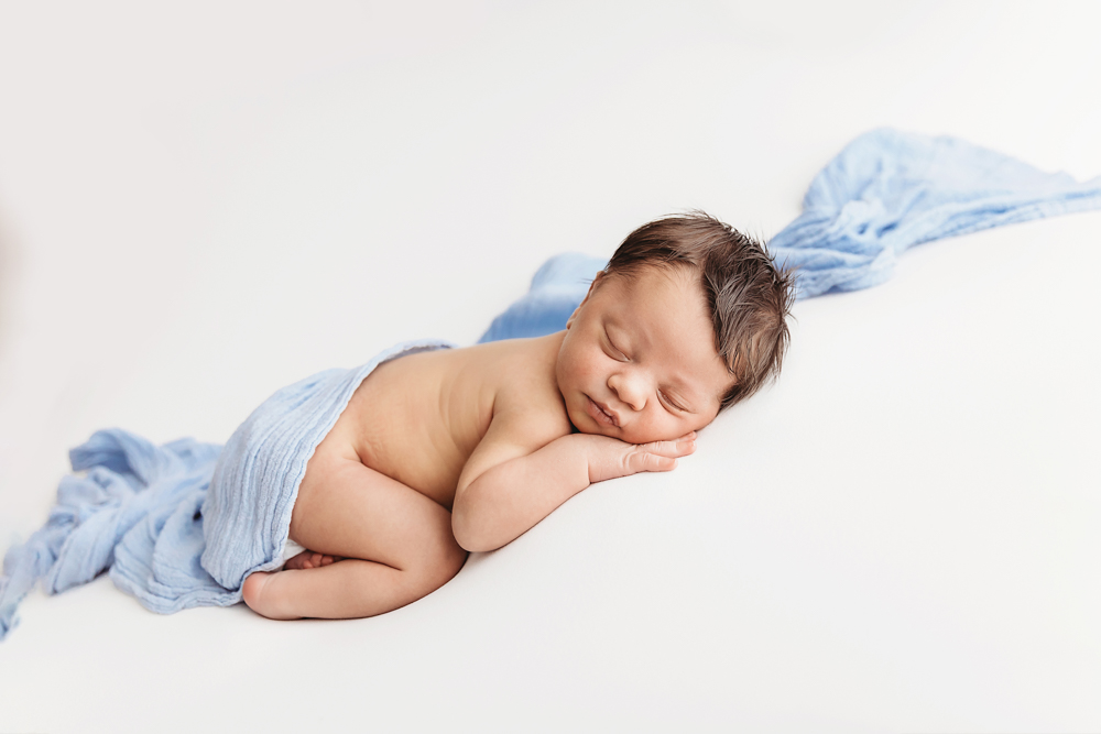 Liston posed on side in taco pose with blue wrap flowing softly on white blanket at Reflection Images by Tracy Rowell in Florence SC
