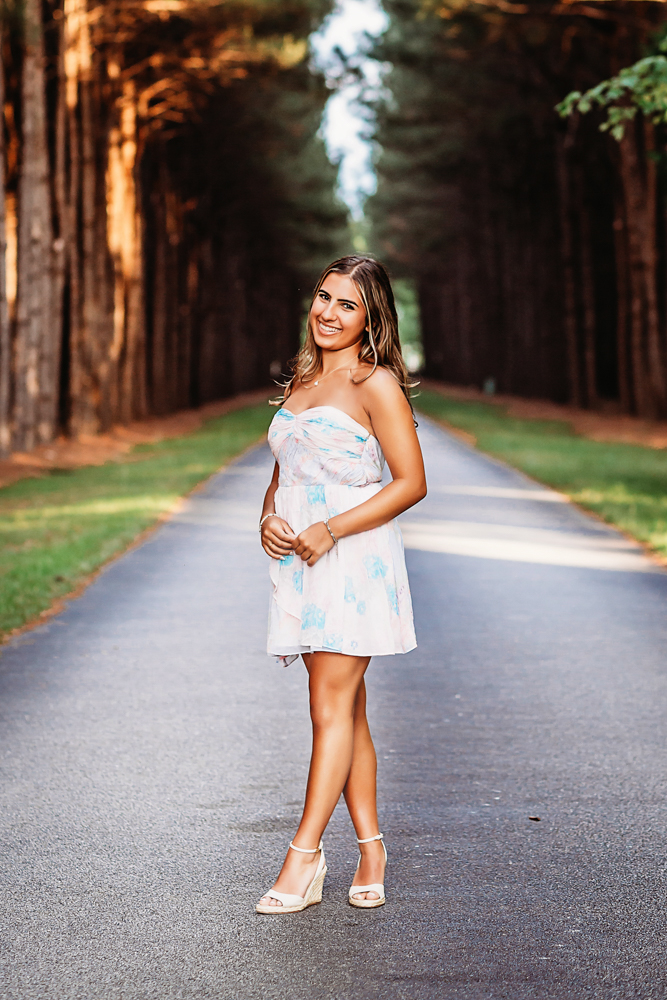 Senior session photo taken in golden hour at golden hour, showing a standing pose in casual style from a eye-level angle