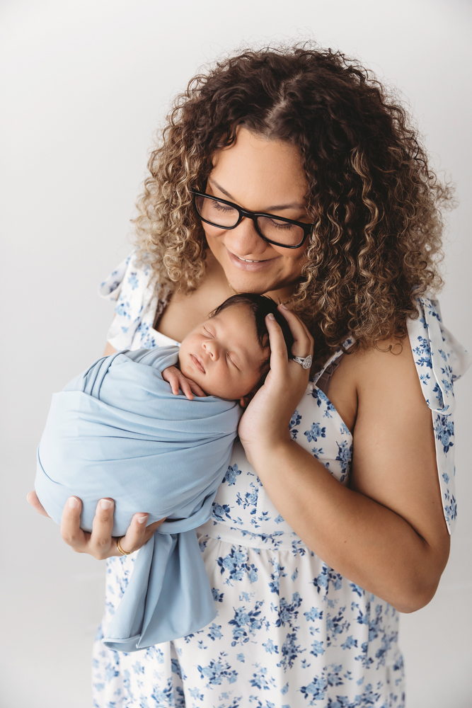 Mom beaming down at swaddled baby Liston in blue wrap, cradled lovingly in her arms at Reflection Images by Tracy Rowell in Florence SC
