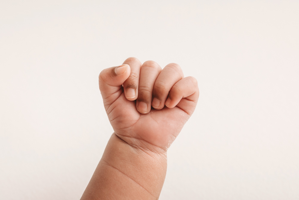 Close-up of Braylens tiny curled hand against a creamy backdrop at Reflection Images by Tracy Rowell in Florence SC