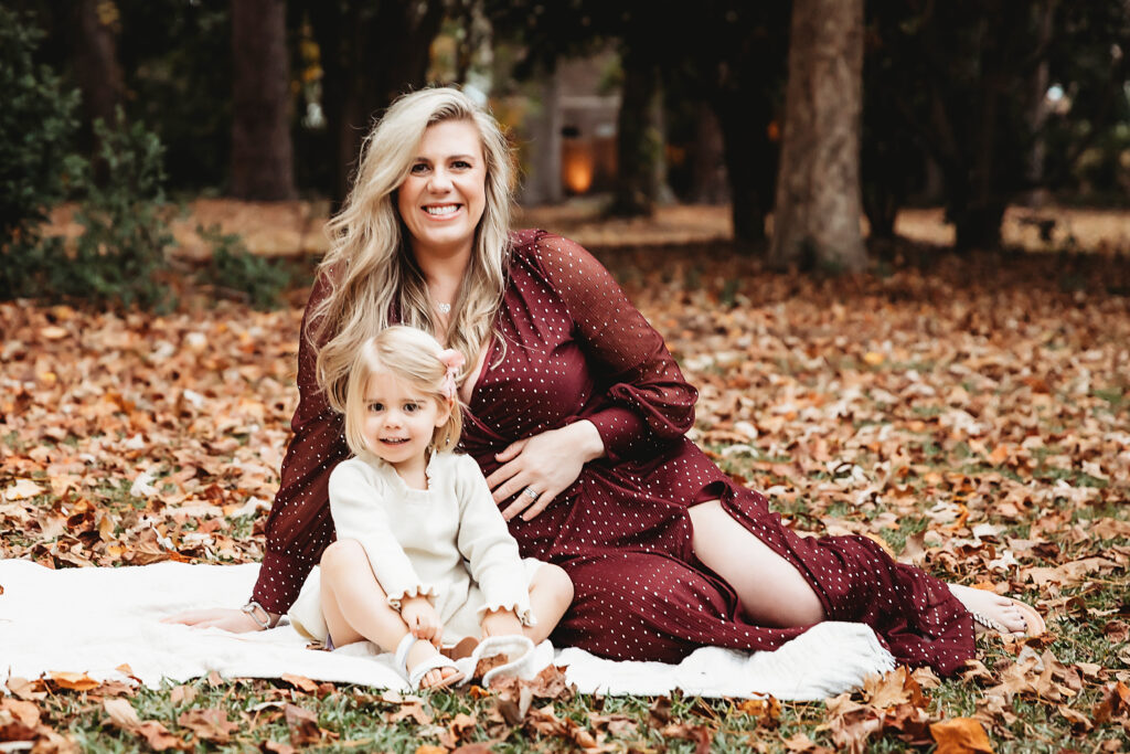 Mother and daughter relaxing on blanket surrounded by autumn leaves