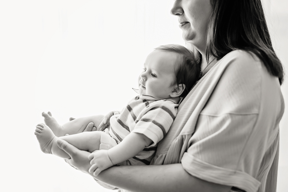 Mom holding baby in front of bright window, professional milestone session Florence SC