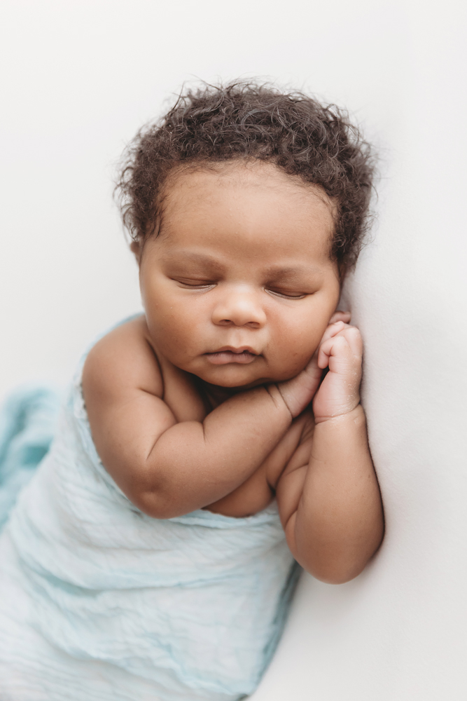 Close-up of Braylen resting with folded arms in soft textured light blue wrap, hair and cheeks detailed at Reflection Images by Tracy Rowell in Florence SC