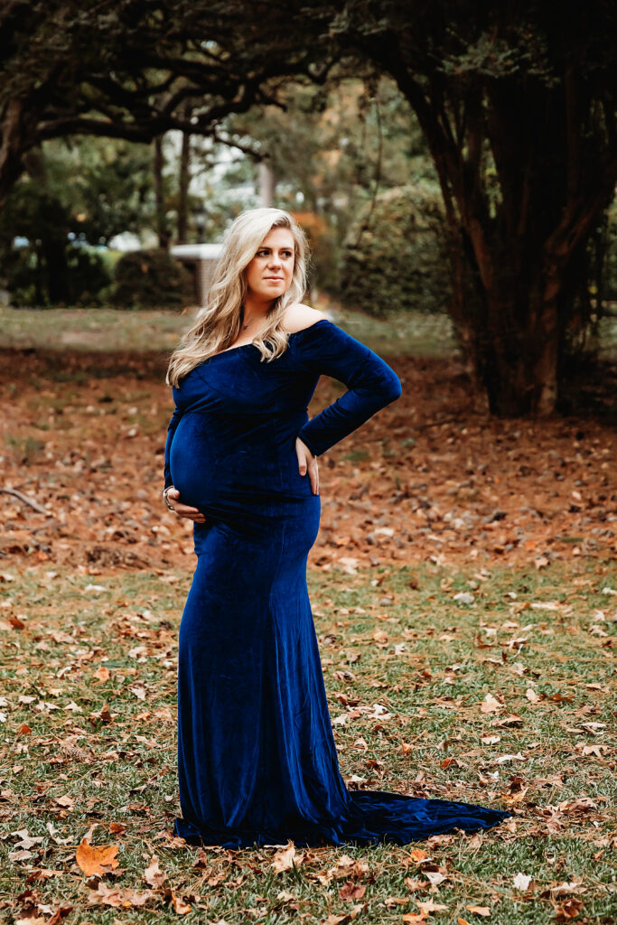 Pregnant mom standing confidently under tree canopy in blue dress