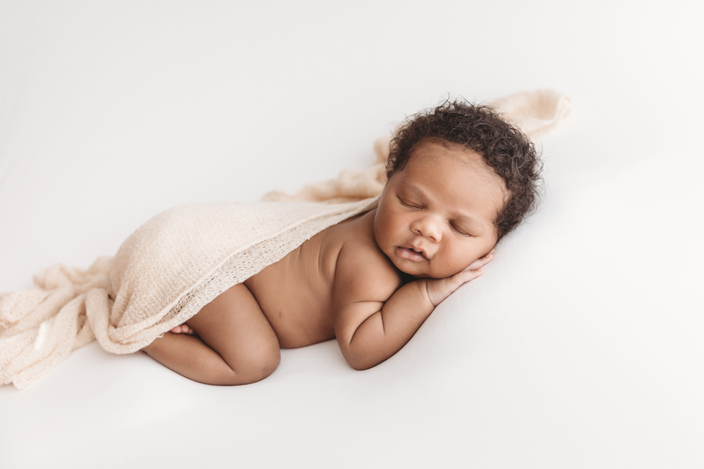 Braylen sleeping soundly under a loose knit beige wrap with hand tucked under cheek on soft white background at Reflection Images by Tracy Rowell in Florence SC