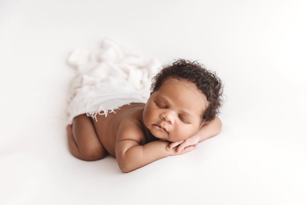 Braylen in a lightly fringed cream wrap stretched out on white posing fabric, eyes closed at Reflection Images by Tracy Rowell in Florence SC