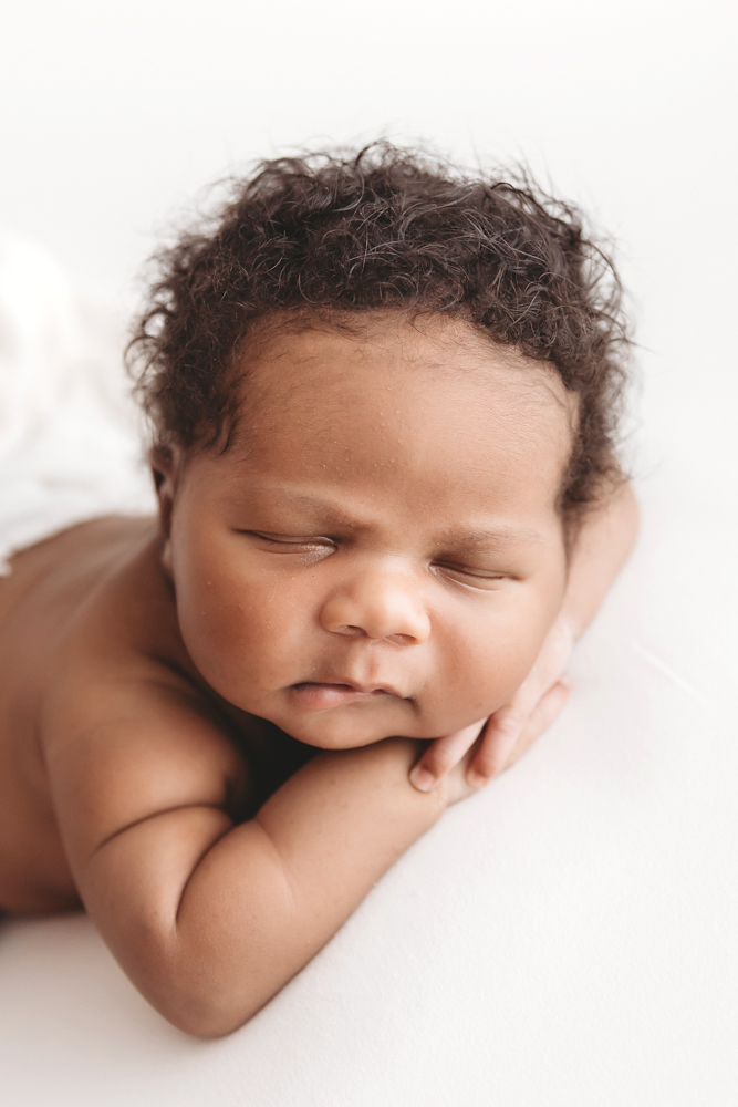 Braylen in a lightly fringed cream wrap stretched out on white posing fabric, eyes closed at Reflection Images by Tracy Rowell in Florence SC