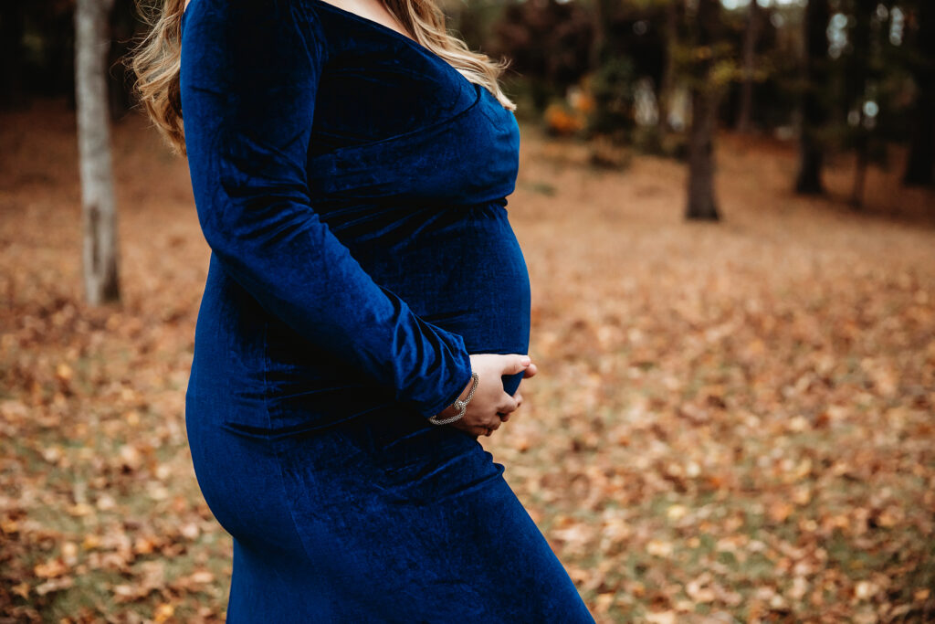 Close-up of pregnant belly in rich blue velvet gown