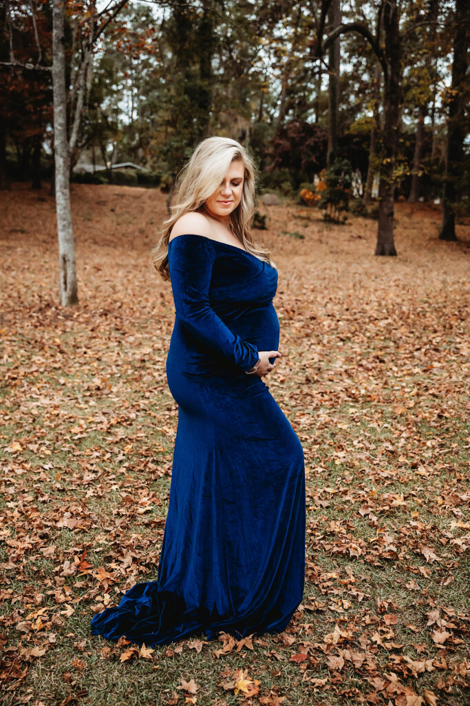Side profile maternity portrait in navy gown with hand on belly