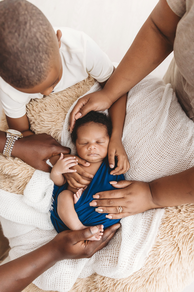 Newborn baby Braylen asleep in a woven basket with layered blankets