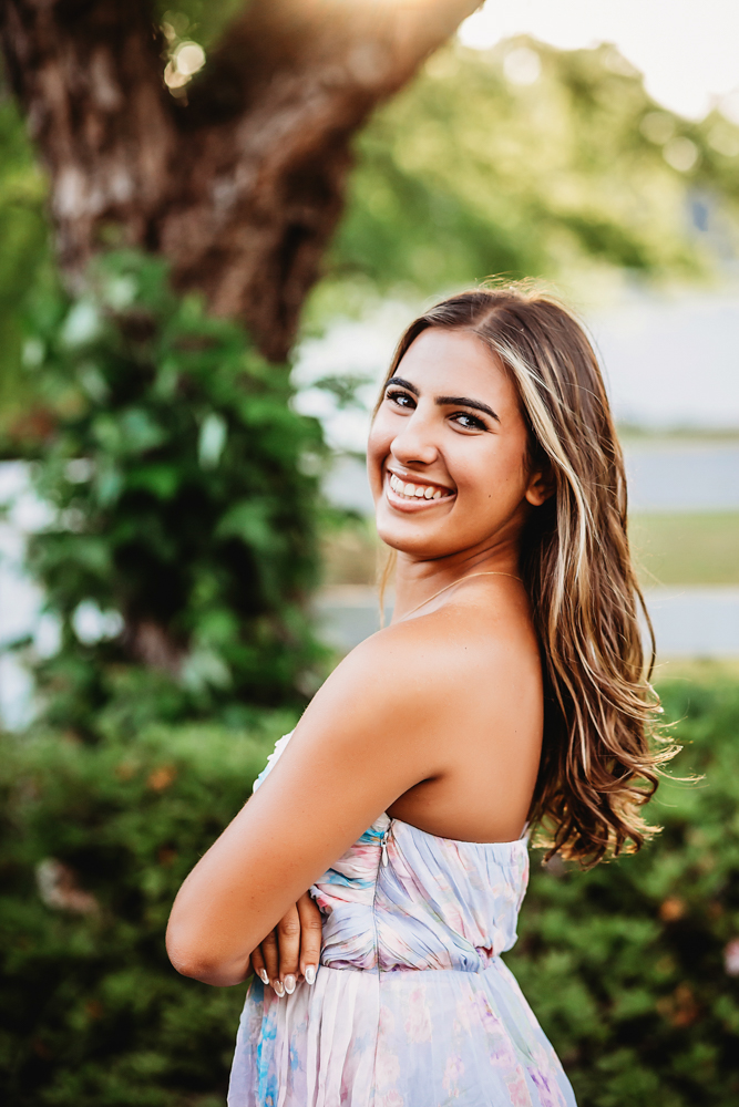 Senior session photo taken in sunlit trail at golden hour, showing a walking pose in casual style from a eye-level angle