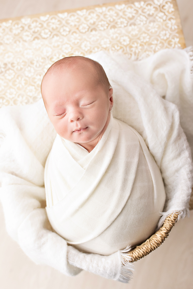 overhead newborn Walker swaddled in ivory wrap snug in basket with white layers near Florence SC
