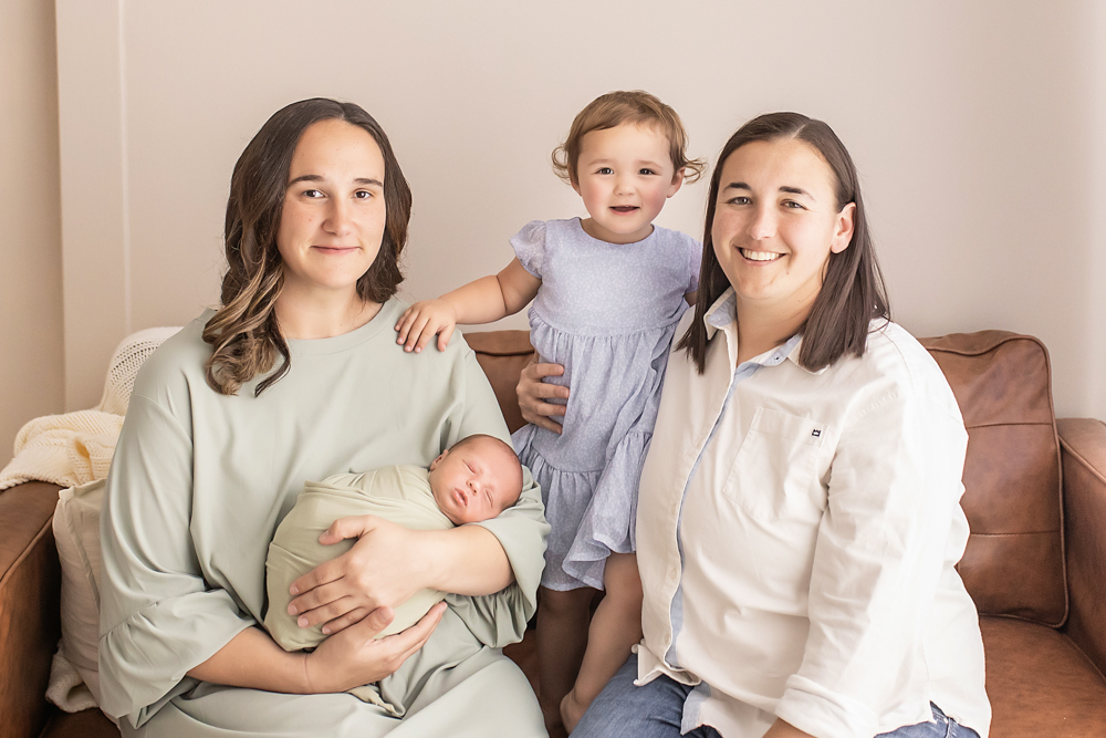 family of four on caramel couch newborn in sage wrap lifestyle studio portrait Florence SC