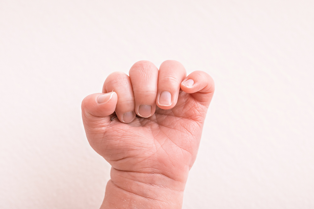 macro of newborn fist and tiny nails against white blanket Florence SC macro photography