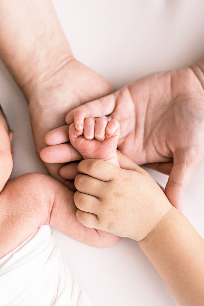 family hands cradling newborn fist generations detail on white Florence SC Photography studio
