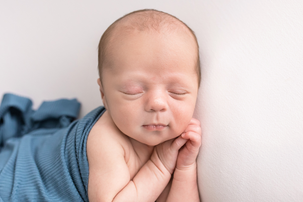 close-up newborn Reflection Images Walker sleeping in teal ribbed wrap against white Florence SC