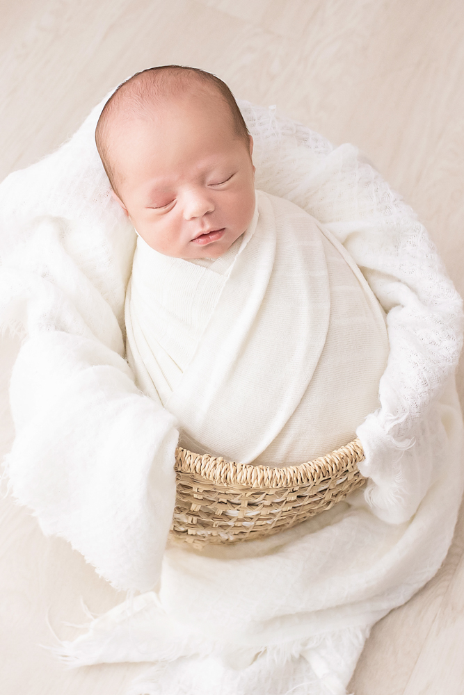 vertical portrait newborn tightly wrapped in ivory nestled in wicker basket Florence SC
