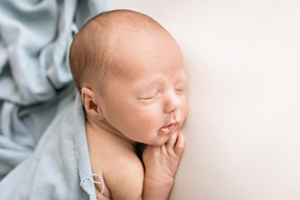 close-up of newborn Walker on white with pale blue drape cheek to blanket Florence SC