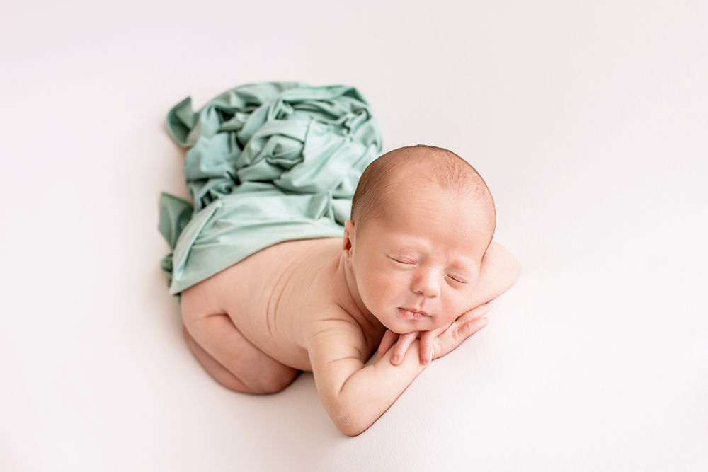chin-on-hands pose newborn Walker with mint drape on white beanbag Florence SC
