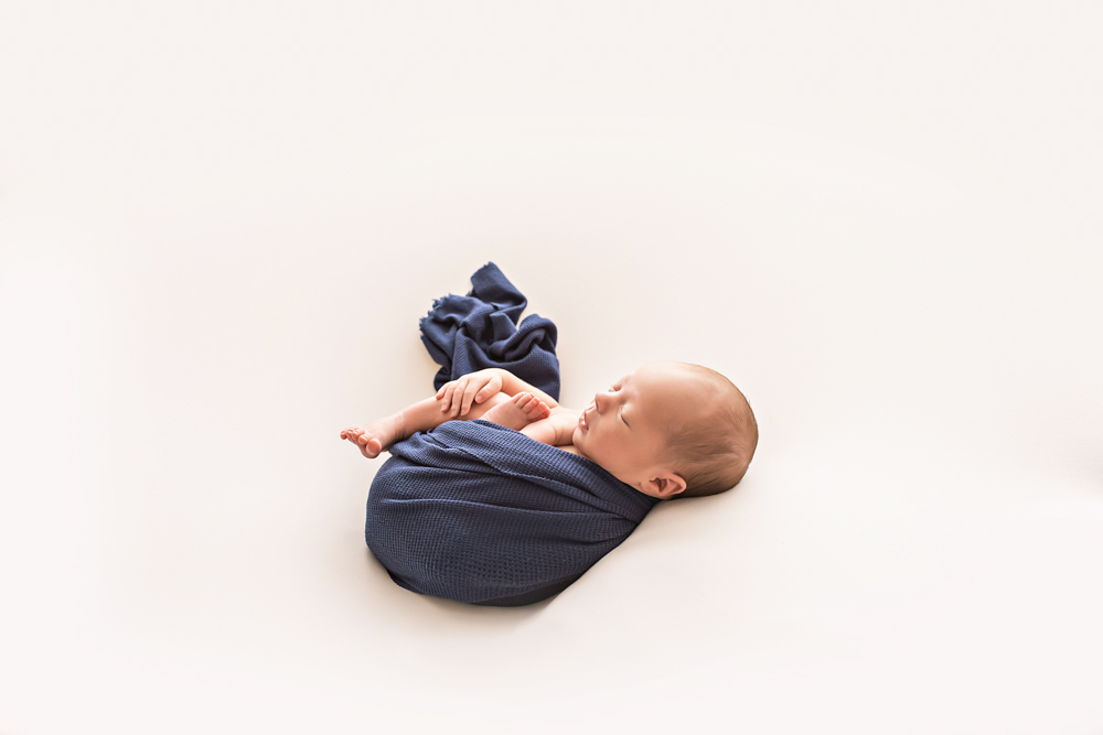 minimalist wide shot newborn Walker in navy wrap on seamless white Florence SC studio