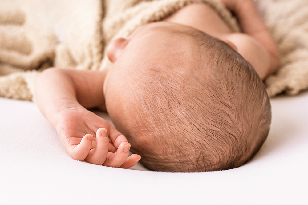 detail of newborn crown and tiny hand resting on white blanket Florence SC Reflection images macro images