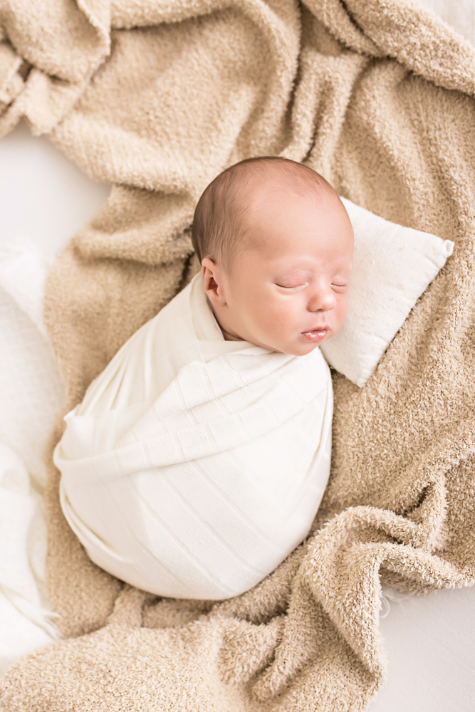 newborn Walker wrapped in white on tan textured blanket tiny pillow Florence SC