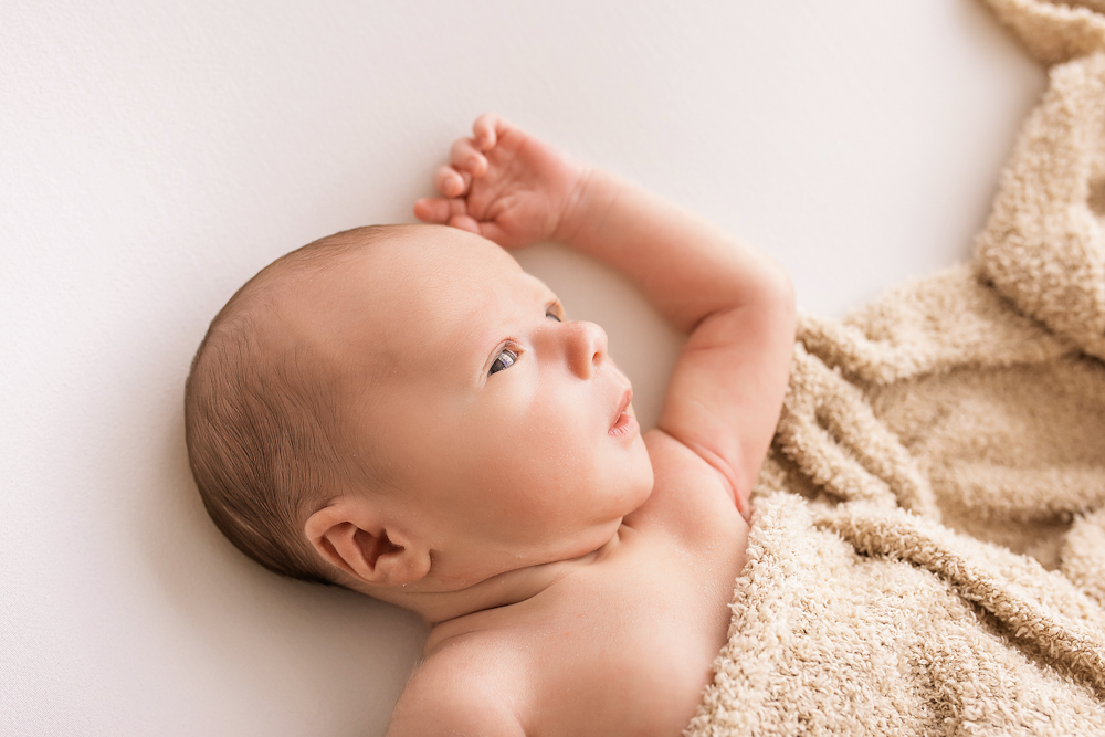 awake profile of newborn Walker wrapped in tan blanket soft natural light Florence SC professional photography