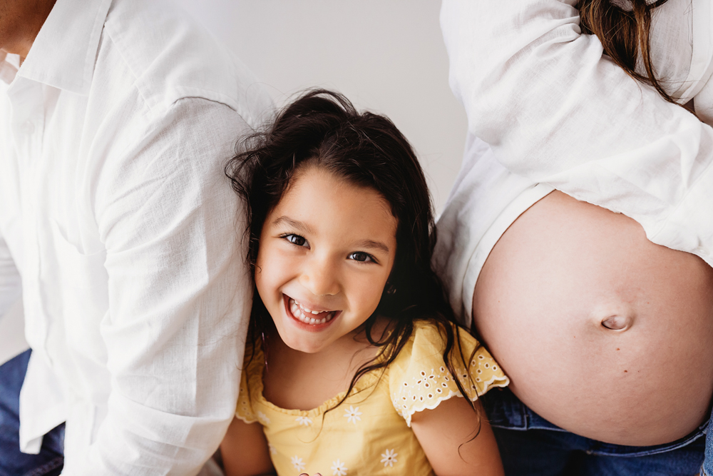 Buenrostro belly closeup with daughter in bright natural light and clean studio backdrop at Reflection Images by Tracy Rowell in Florence SC