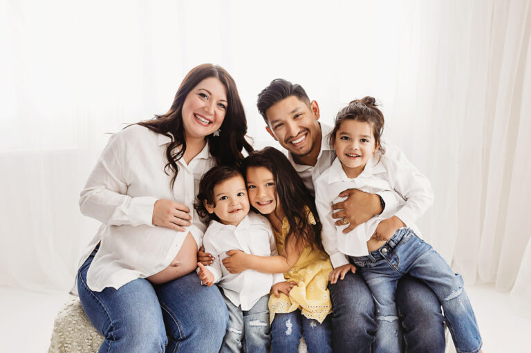 Buenrostro family on couch snuggles in bright natural light and clean studio backdrop at Reflection Images by Tracy Rowell in Florence SC