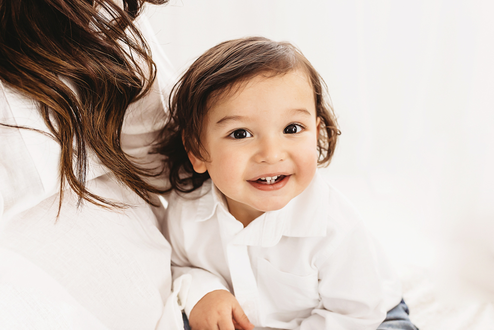 Buenrostro mom holding toddler smile in bright natural light and clean studio backdrop at Reflection Images by Tracy Rowell in Florence SC