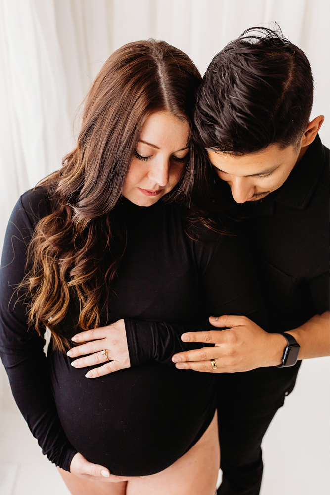 Buenrostro parents hands on belly in warm, joyful feel with candid connection at Reflection Images by Tracy Rowell in Florence SC